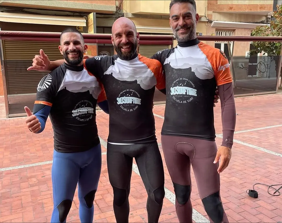 Tres monitores de la escuela sonriendo con las licras de 3RJ Surf Time