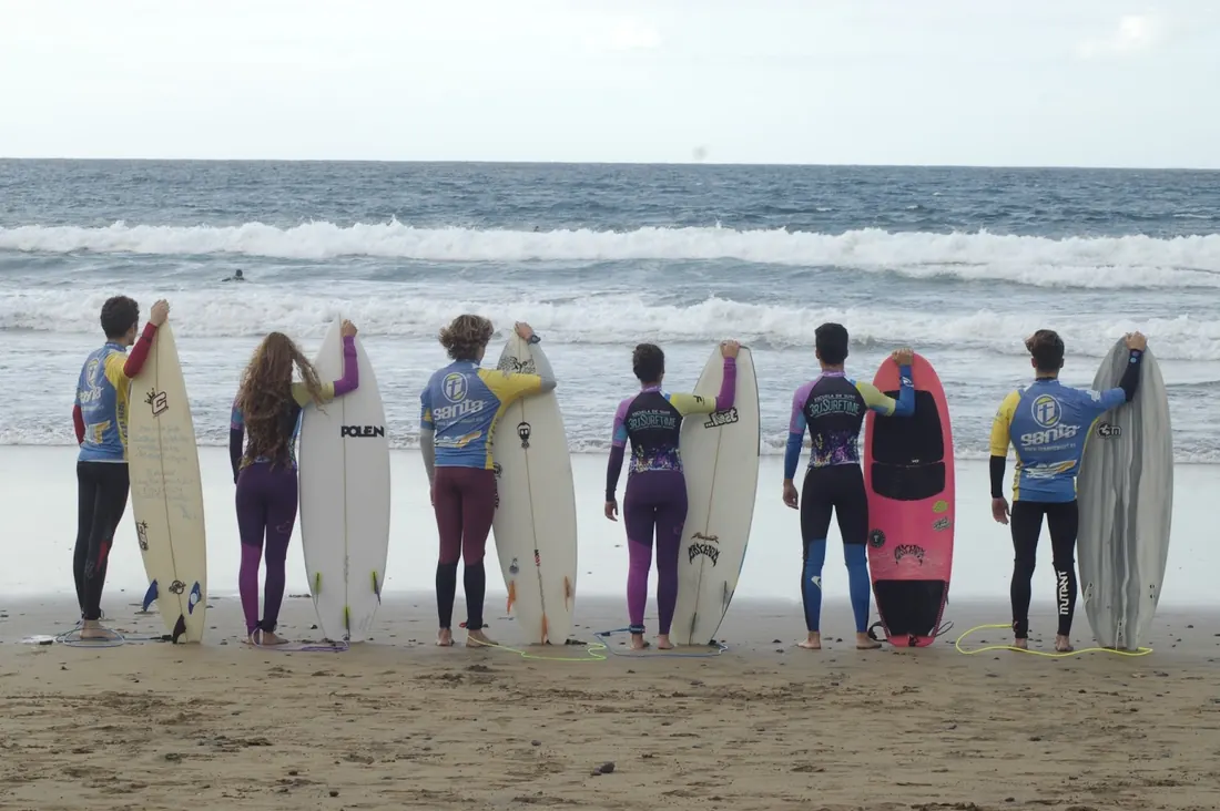 Grupo de alumnos de espaldas con sus tablas mirando el mar